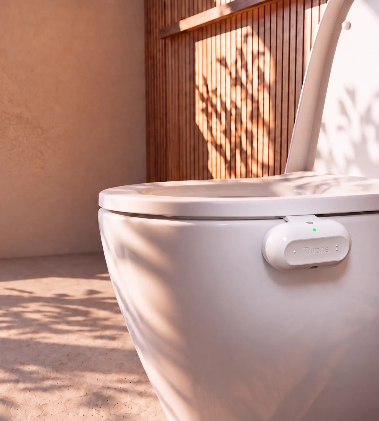 Throne sensor clipped to a white toilet bowl in a sunlit bathroom