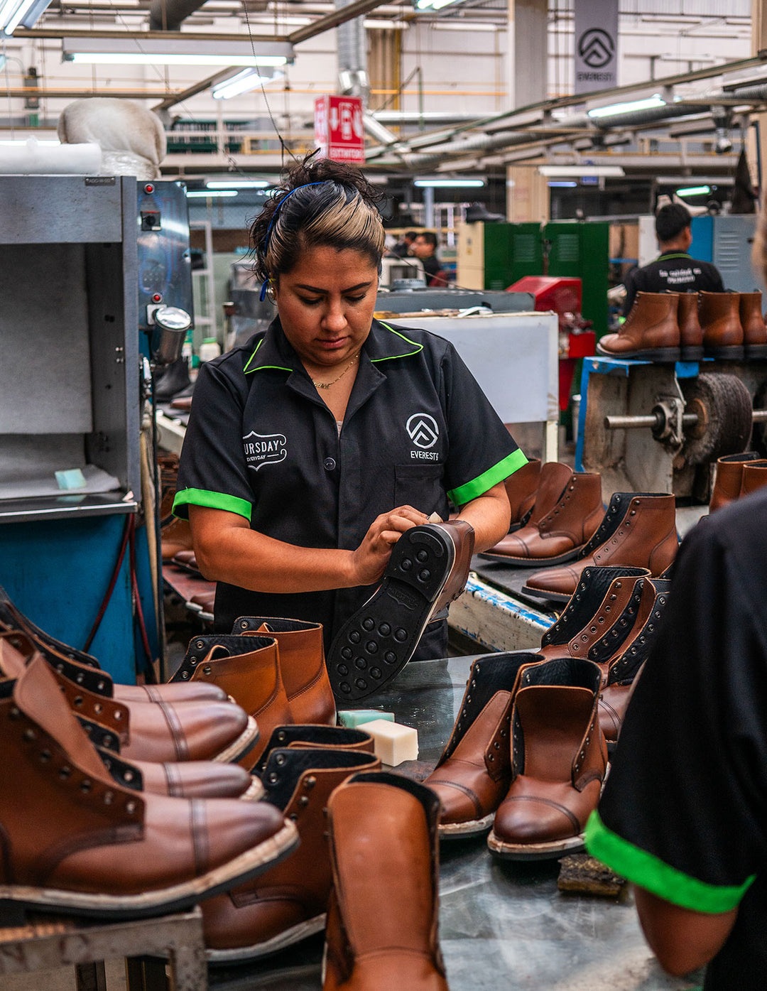 A factory worker inspects a Thursday boot amid rows of boots in production
