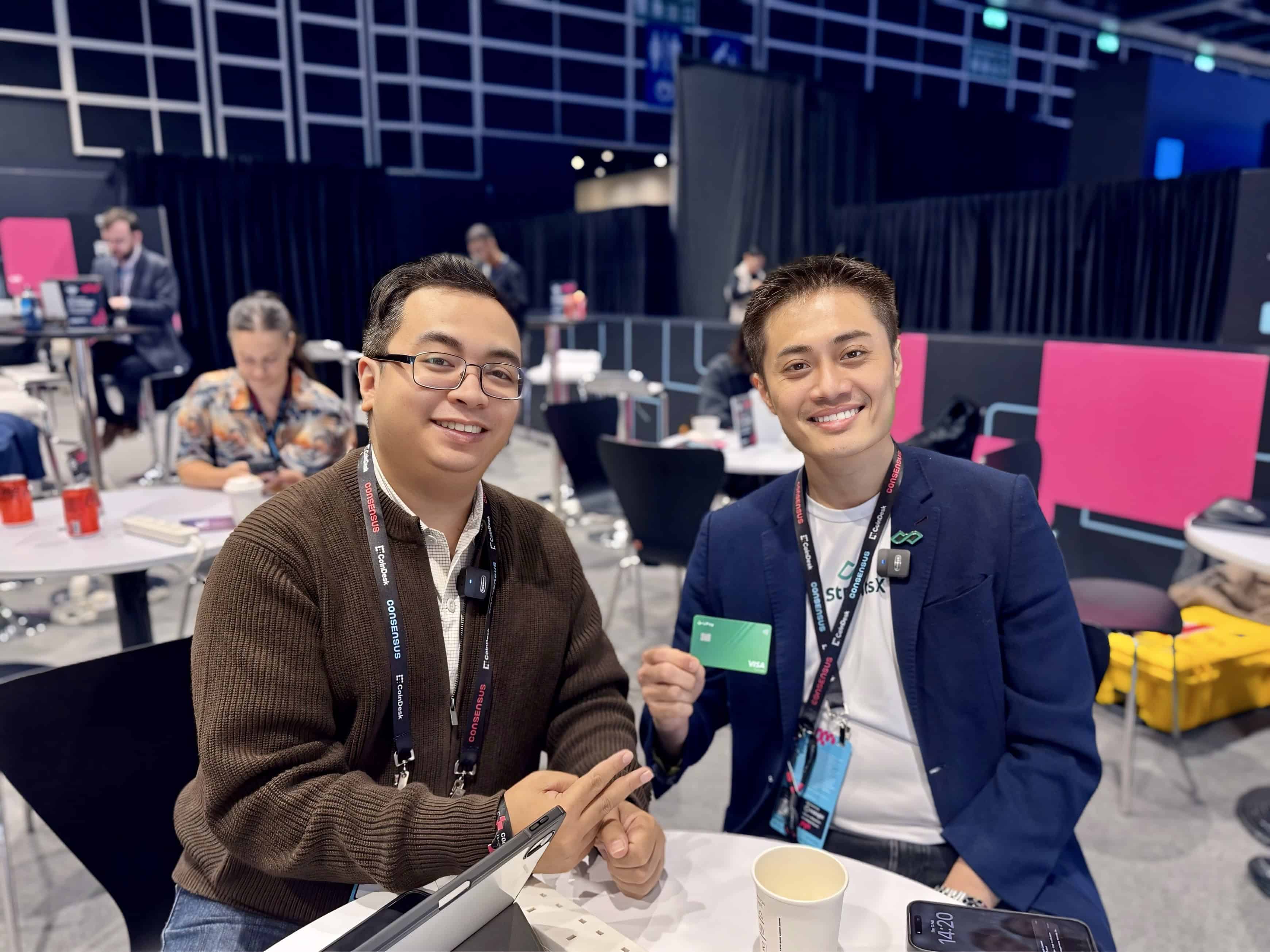 Michael Mislos, left, and Tianwei Liu, right, holding a Visa card at Consensus Hong Kong 2026