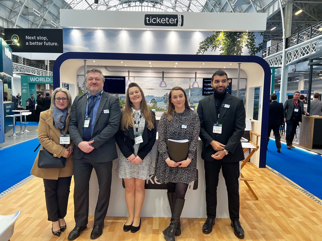 Five Ticketer representatives standing at the company’s bus-shaped exhibition stand at Olympia London in 2024