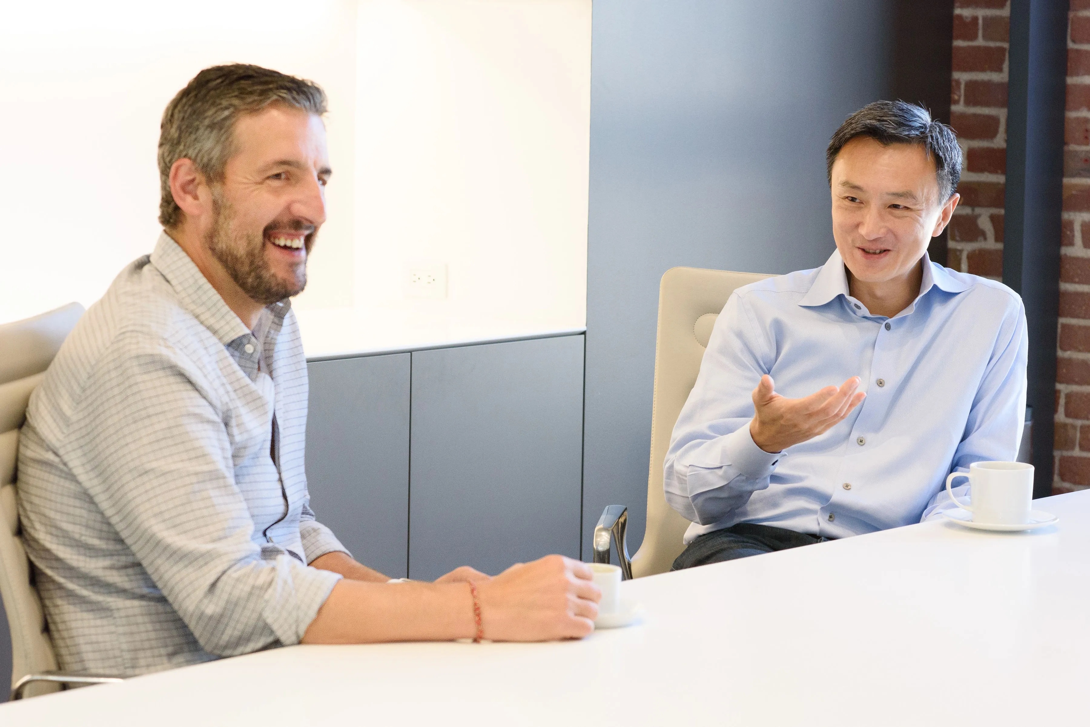 Mike Volpi, left, smiling in conversation with Tien Tzuo, right, at a table with coffee cups
