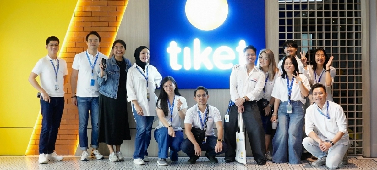 A group of tiket.com employees posing together in a yellow-and-blue office space
