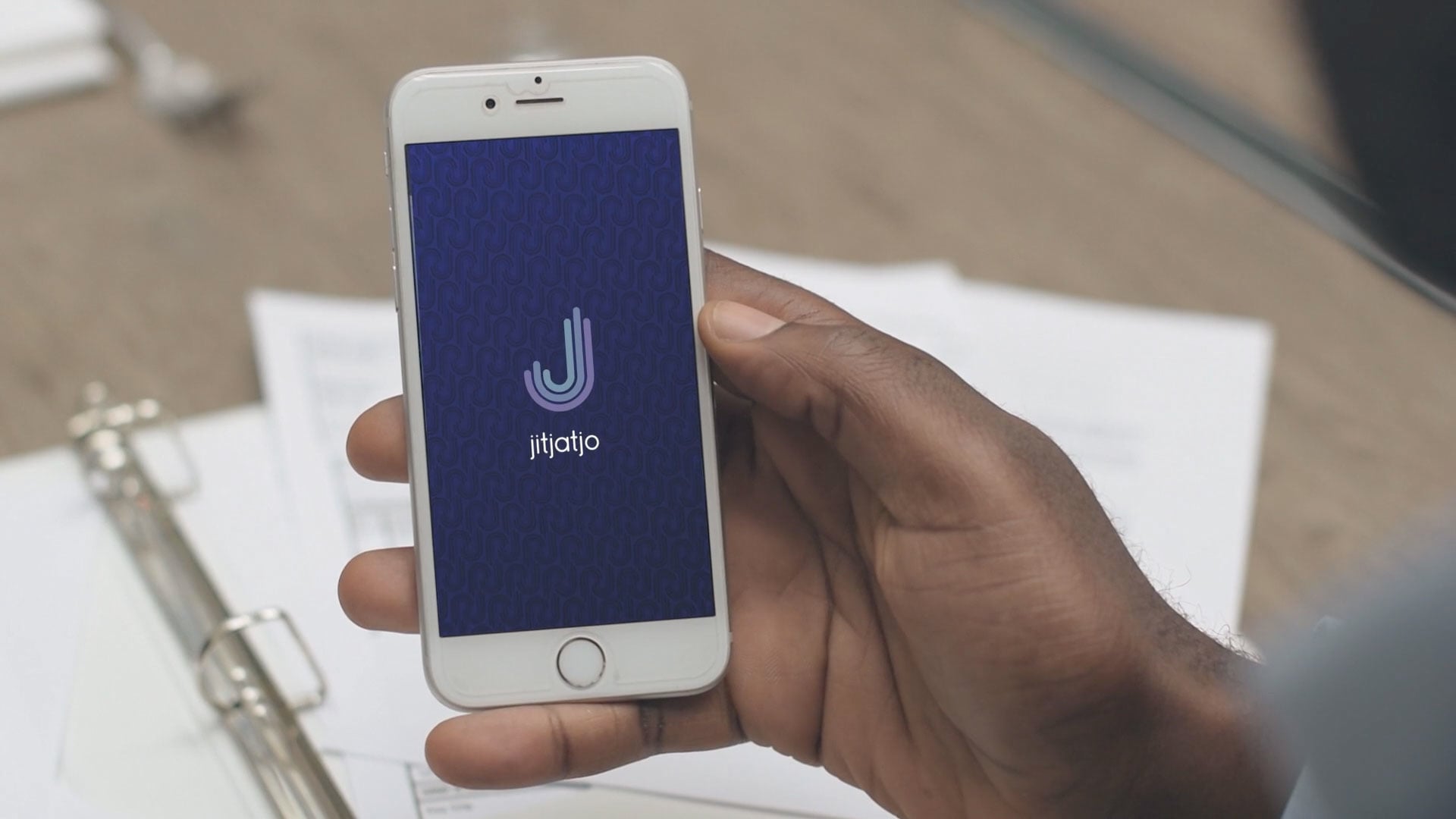 A hand holds a phone displaying the early Jitjatjo app
