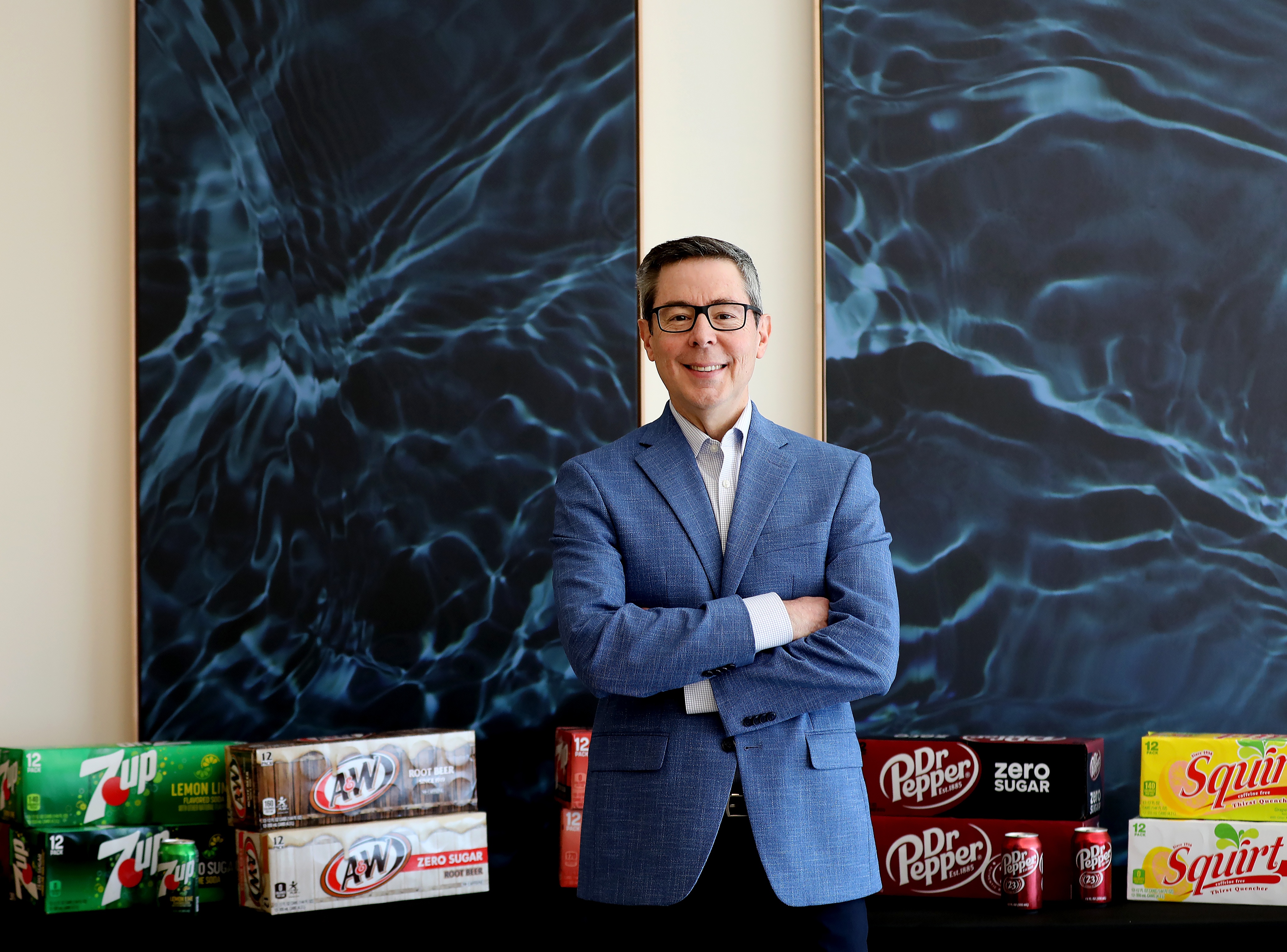 Tim Cofer at Keurig Dr Pepper's Frisco office, with cases of the company's beverages behind him.