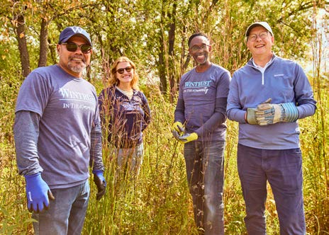Four Wintrust volunteers at Greenbelt Forest Preserve, with Tim Crane at the right wearing gloves