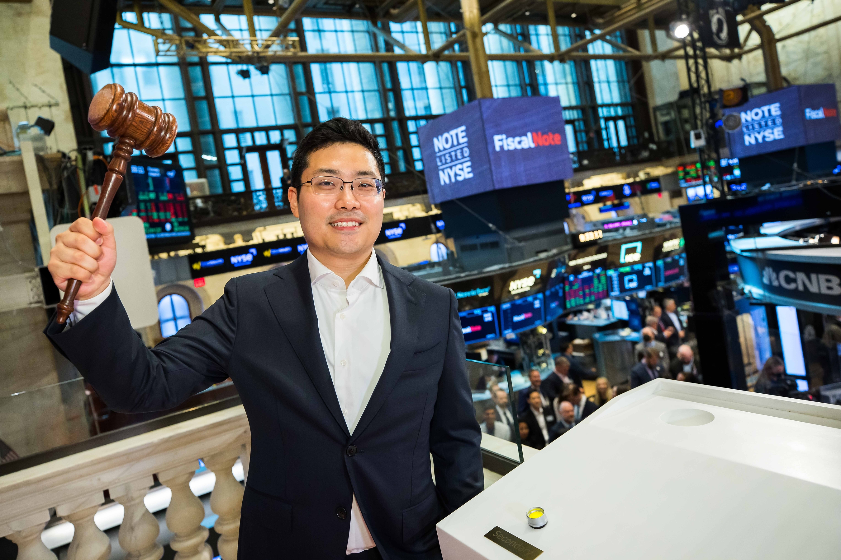 Tim Hwang holding a ceremonial gavel at the New York Stock Exchange during FiscalNote’s August 2022 listing celebration