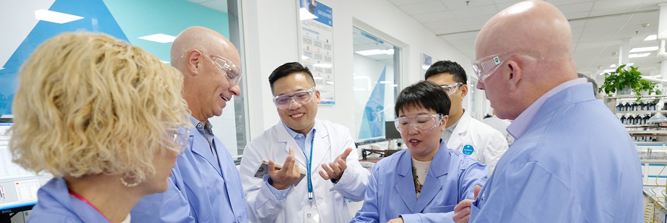 Tim Knavish, second from left, talking with PPG employees wearing protective glasses in a laboratory