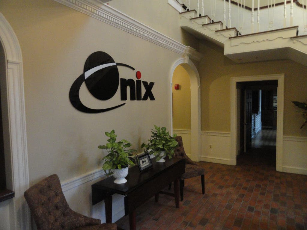 Archival Onix office entrance in Lakewood, with the company’s original logo, brick floor, chairs, and staircase