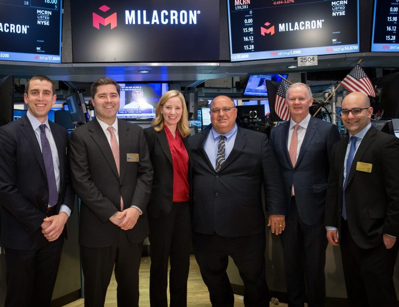 Tim Walsh with a group of CCMP and Milacron colleagues on the New York Stock Exchange floor beneath Milacron displays.