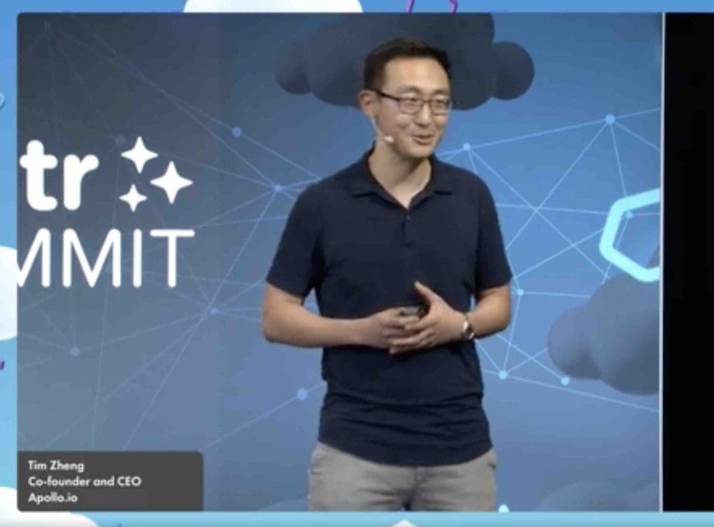 Tim Zheng holding a presentation remote while speaking on a SaaStr stage