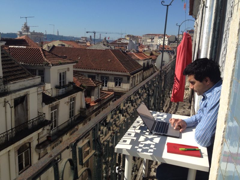 Timoor Taufig working at a laptop on a balcony in Lisbon