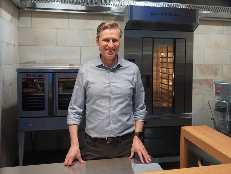 Timothy Fitzgerald standing at a stainless steel counter with Blodgett and Sveba Dahlen ovens behind him.