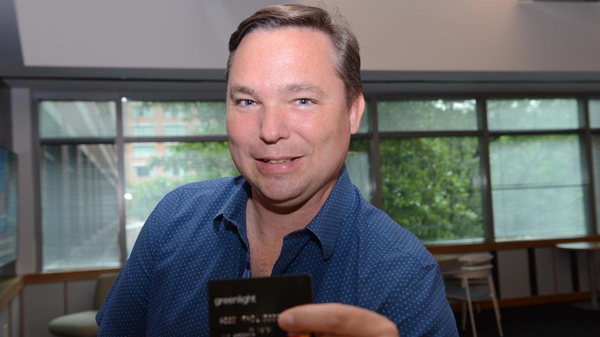 Timothy Sheehan holding a Greenlight card in a bright office