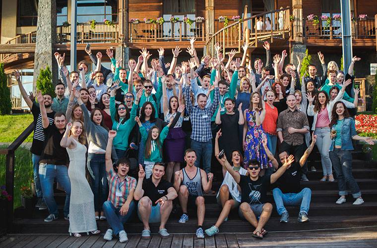 Jivo colleagues gathered outdoors for a team photograph, many raising their hands