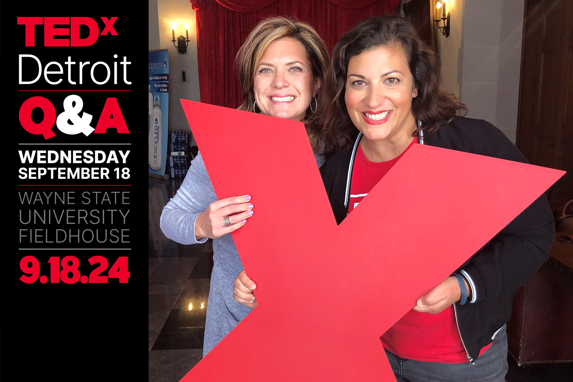 Tina Kozak and another attendee pose with a large red X at a TEDxDetroit event
