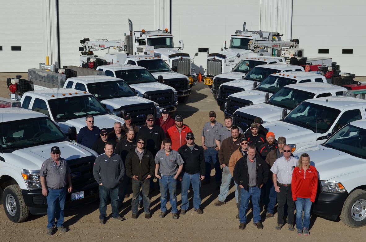 Titan Machinery service staff standing among mobile service trucks outside a workshop