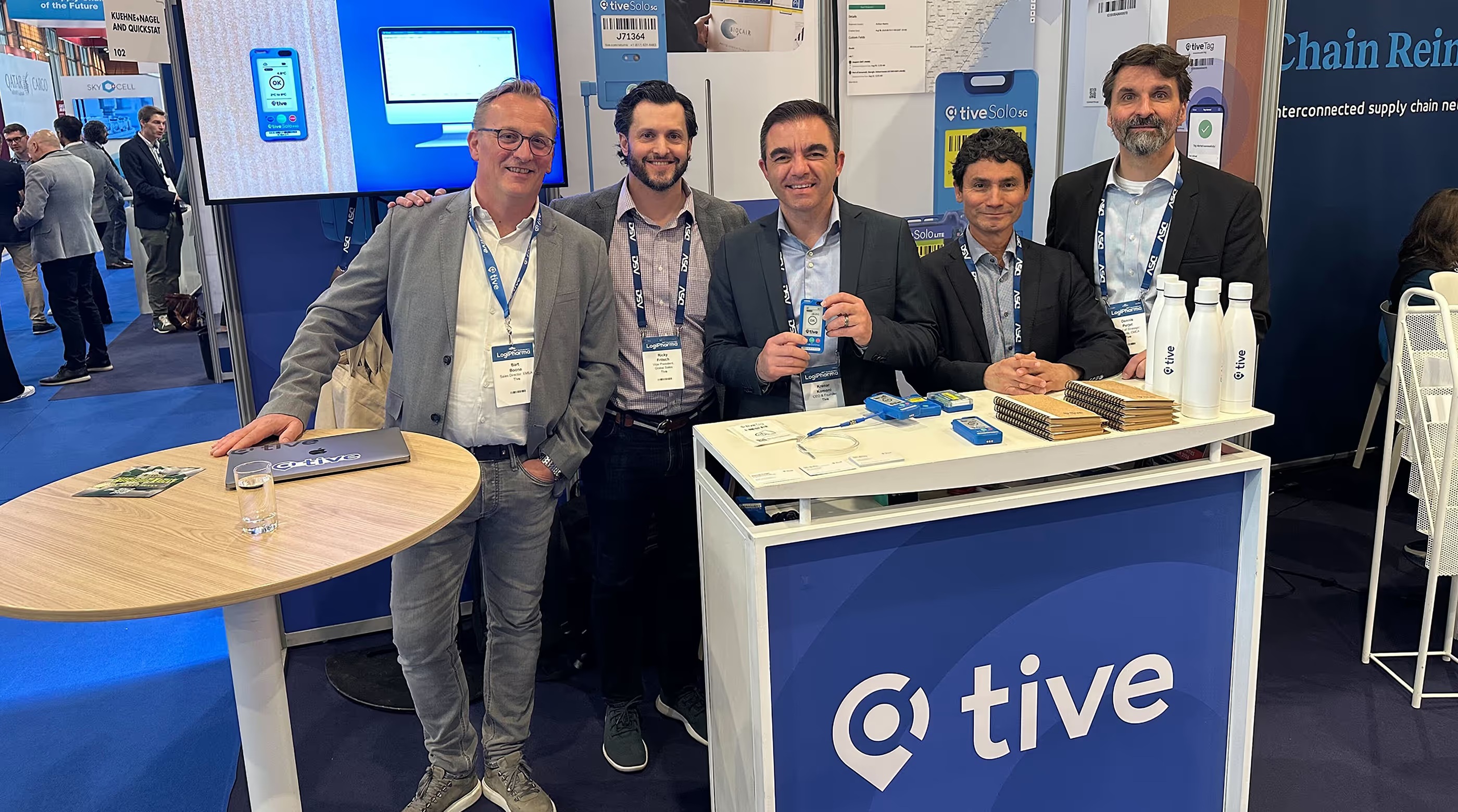 Tive team members at a trade show booth displaying trackers