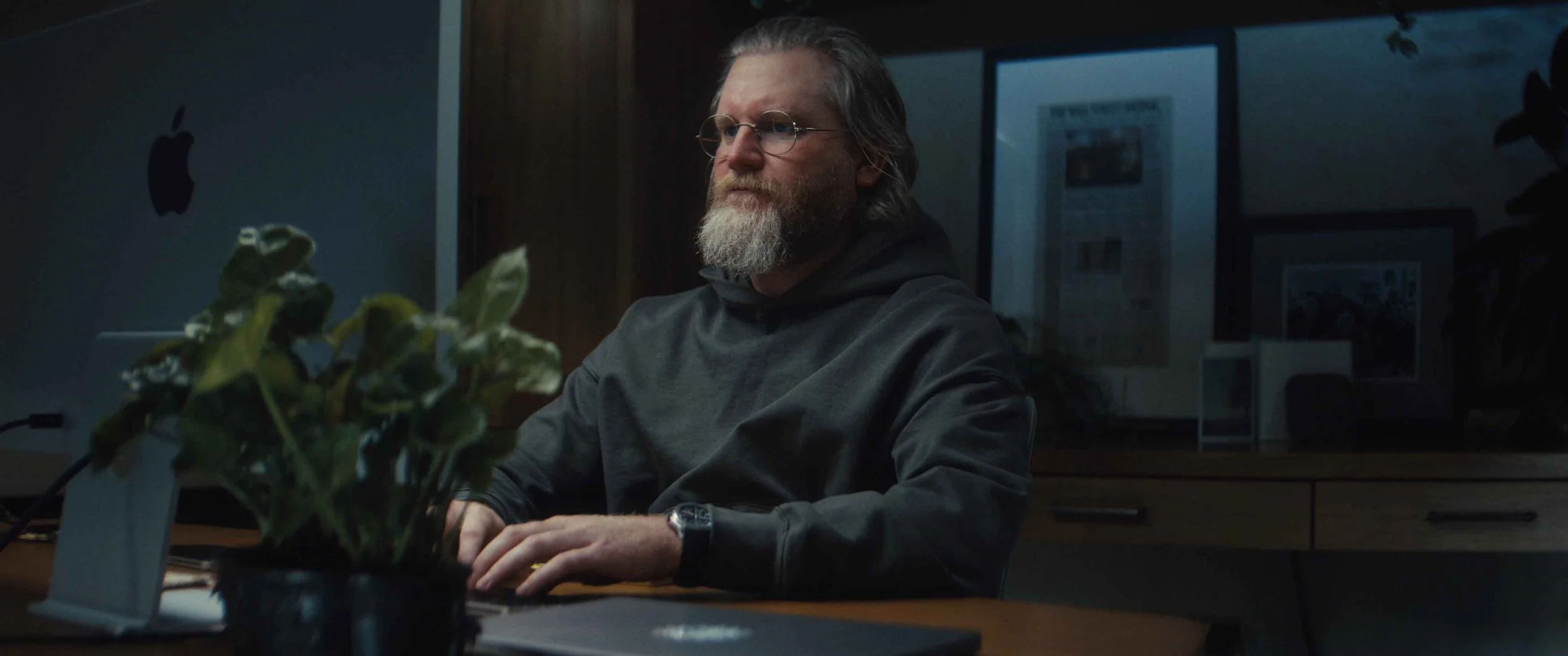 TJ Parker working at a desktop computer, with plants beside his desk