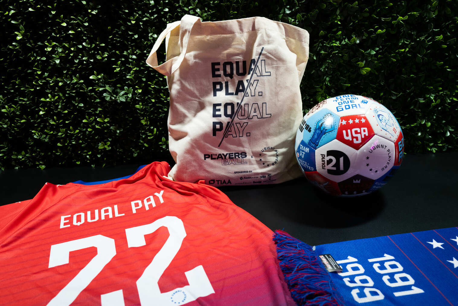 U.S. Women's National Team equal pay merchandise including a jersey, tote bag, scarf, and soccer ball