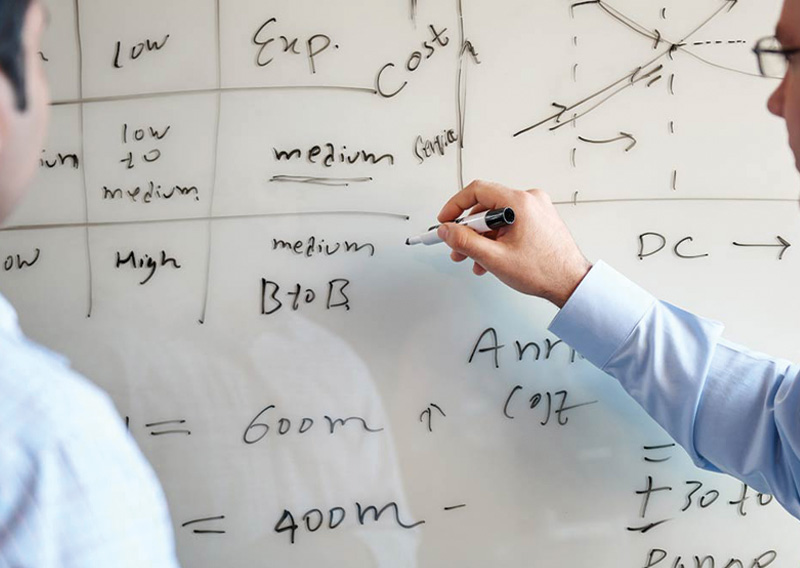 Colleagues working at a whiteboard in an official C.H. Robinson Managed Solutions promotional photograph