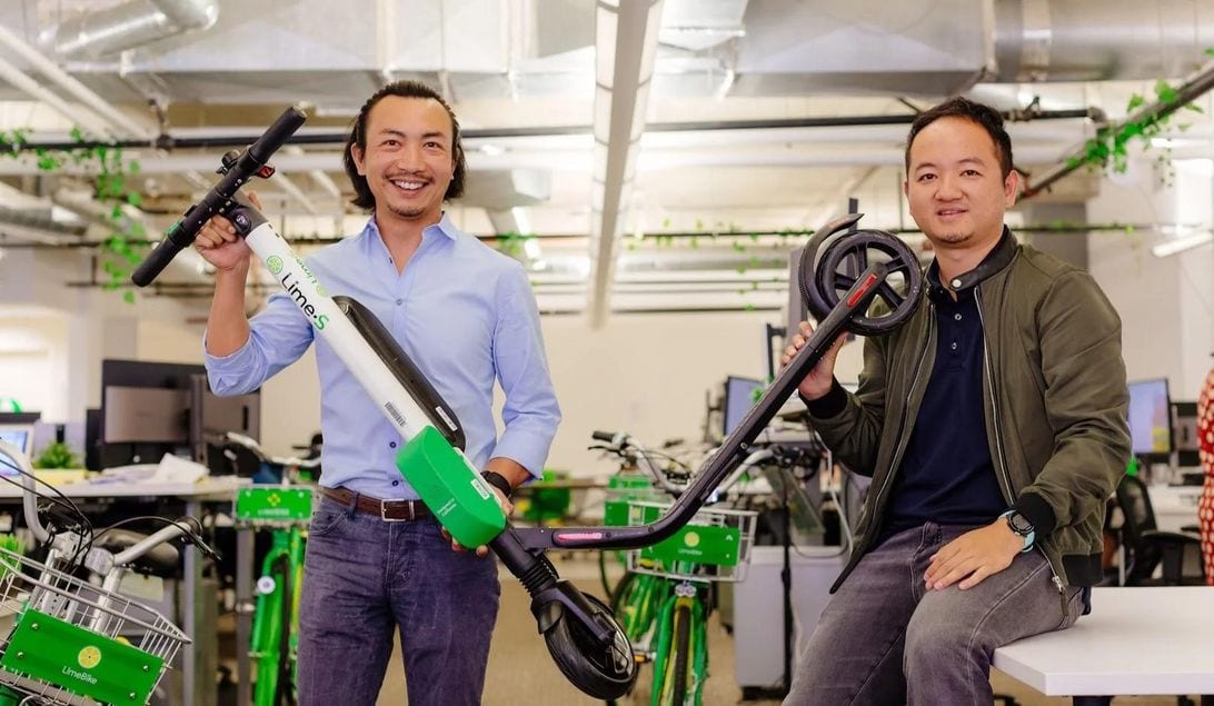 Brad Bao on the left and Toby Sun on the right, holding a Lime scooter in an office
