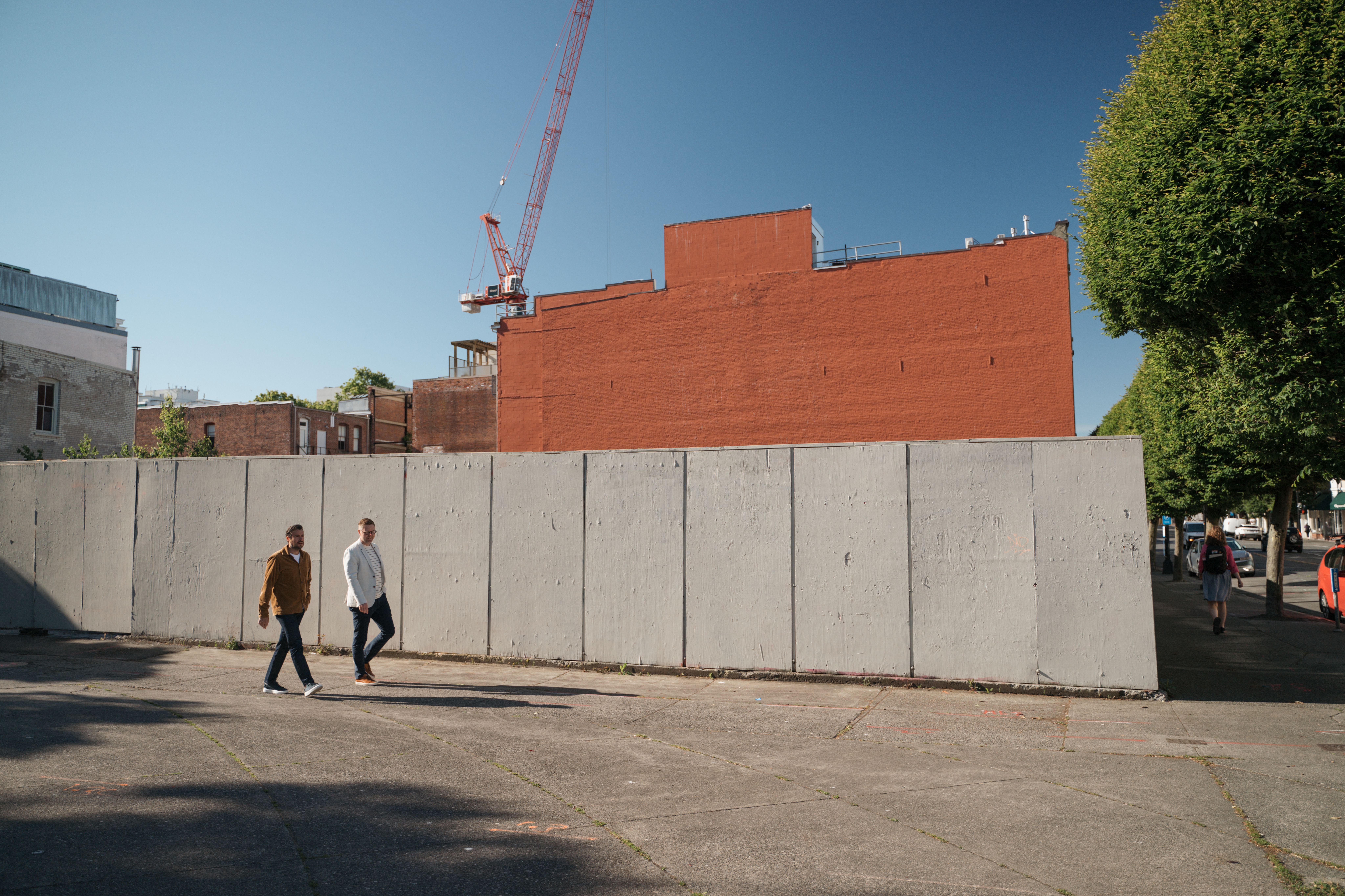Tobyn Sowden, right, walking beside the fenced downtown Victoria hotel site