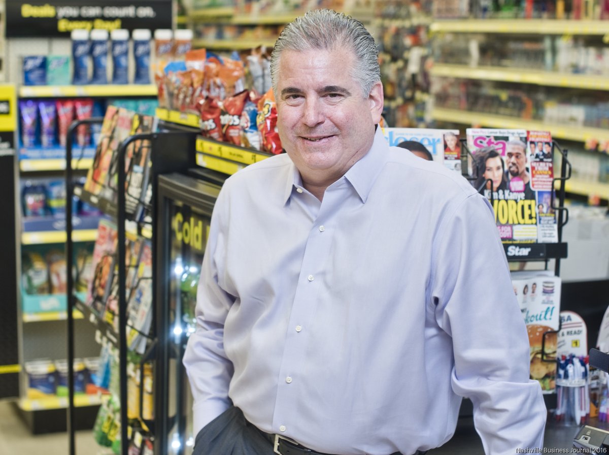 Todd Vasos beside a checkout inside a Dollar General store, surrounded by snacks and magazines