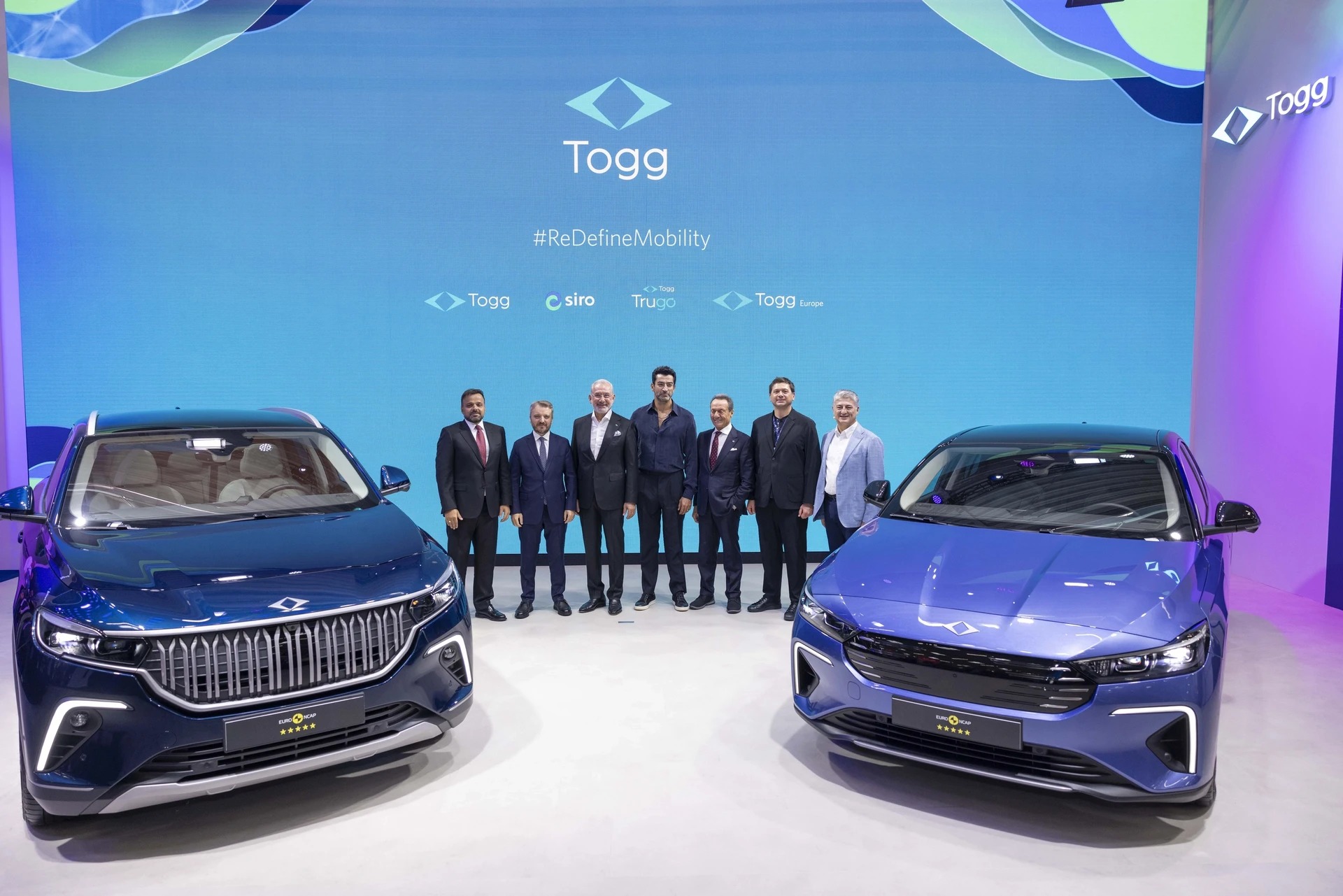 Togg T10X SUV and T10F fastback flanking company representatives at a 2025 event