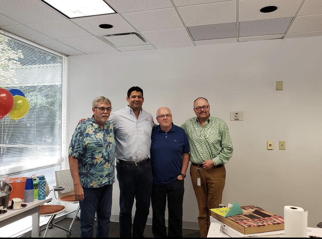 Colleagues gathered in an office for the retirement celebration shown in Tom Burnside’s LinkedIn post