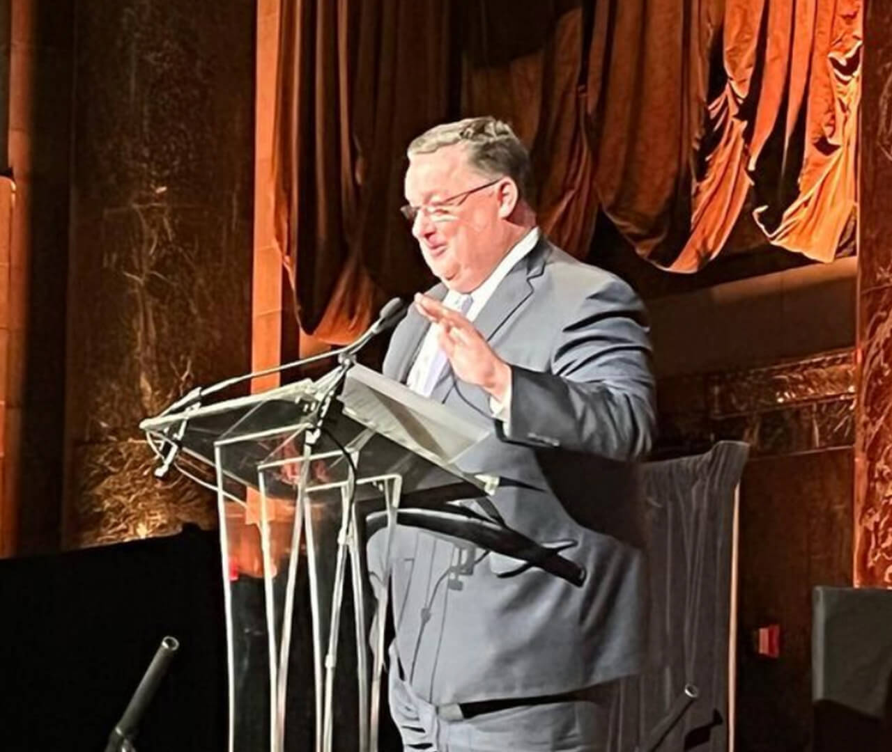 Tom Coyne speaking at a transparent lectern at the 2022 PRNEWS Platinum Awards