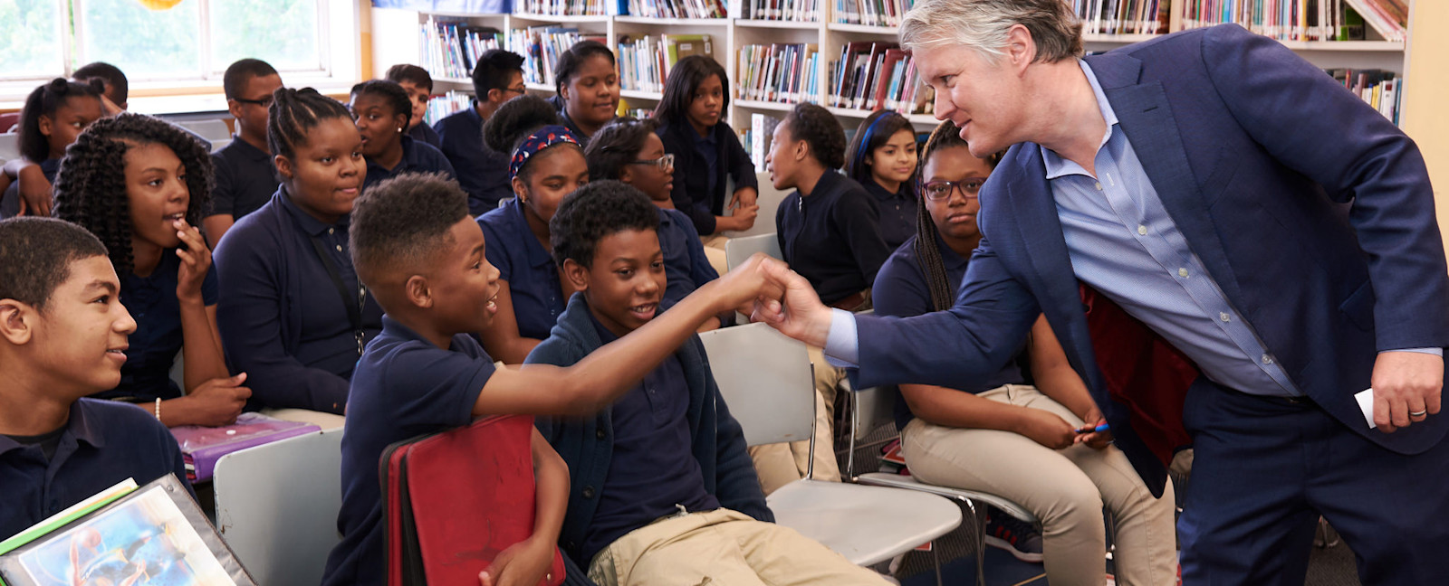 Tom Davidson exchanging a fist bump with a student during a classroom visit