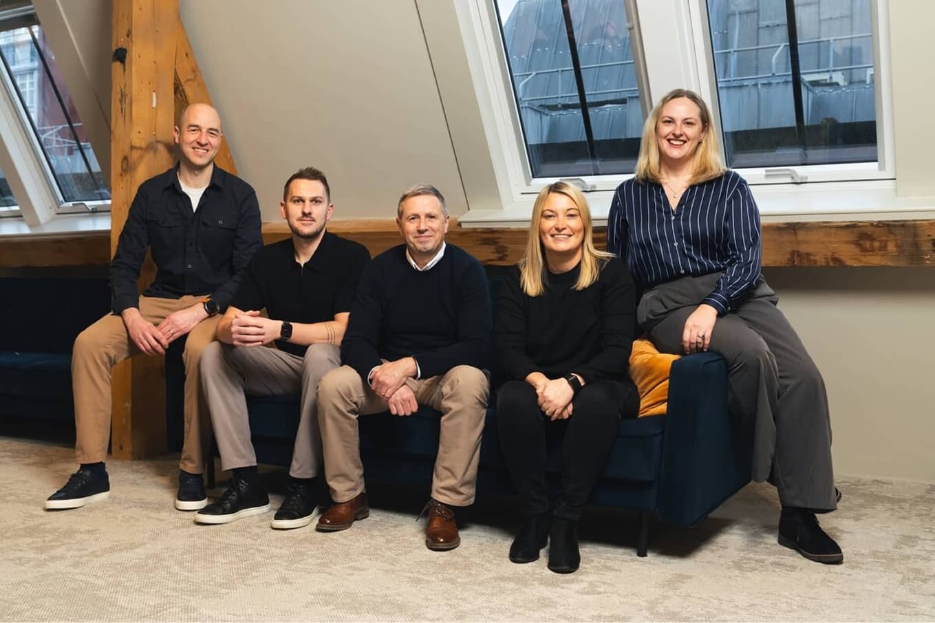 Tom Dunlop, second from left, sits with four colleagues in a timber-beamed office.