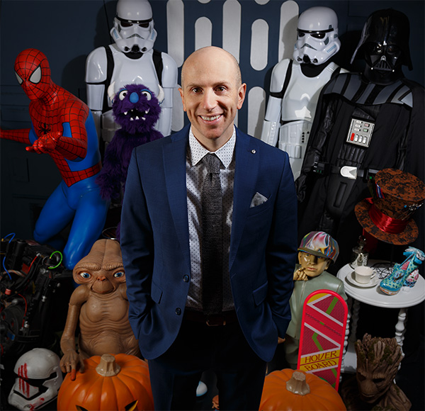 Tom Fallenstein surrounded by movie characters and costume props at FUN.com