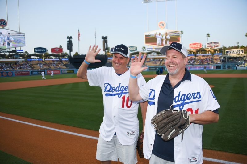 Tom Kelleher, right, wearing a baseball glove, and Bryant Riley wave at Dodger Stadium