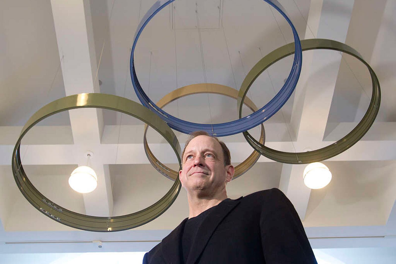 Tom Spann beneath suspended circular sculptures in a 2015 press photograph