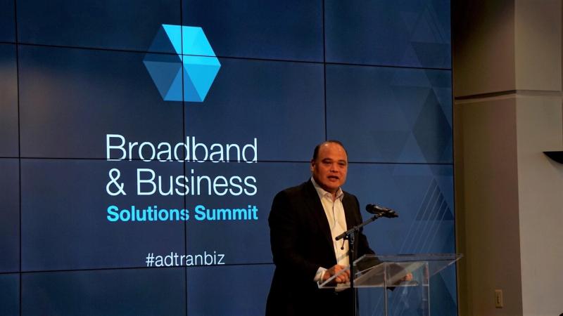 Tom Stanton at a clear lectern opening Adtran’s 2017 Broadband and Business Solutions Summit