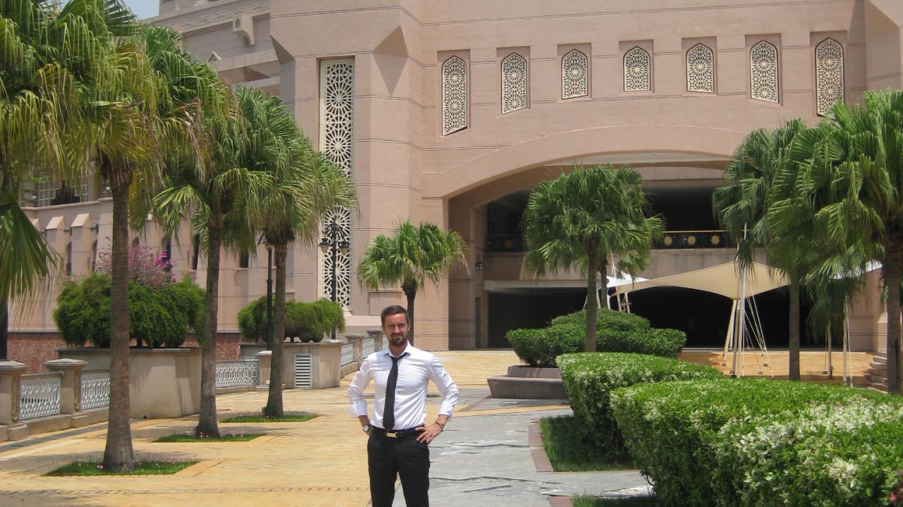 Tomas Milar standing outside a building among palm trees in Kuala Lumpur