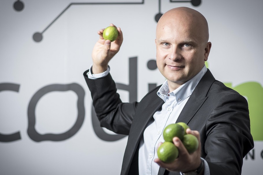 Tomasz Kułakowski holding limes in front of CodiLime branding