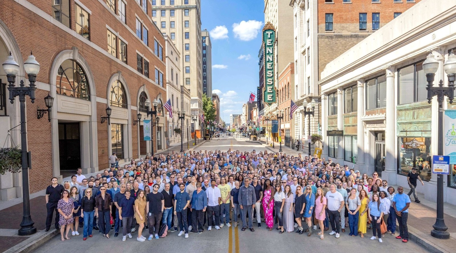 Tombras employees gather on Gay Street with the Tennessee Theatre sign behind them