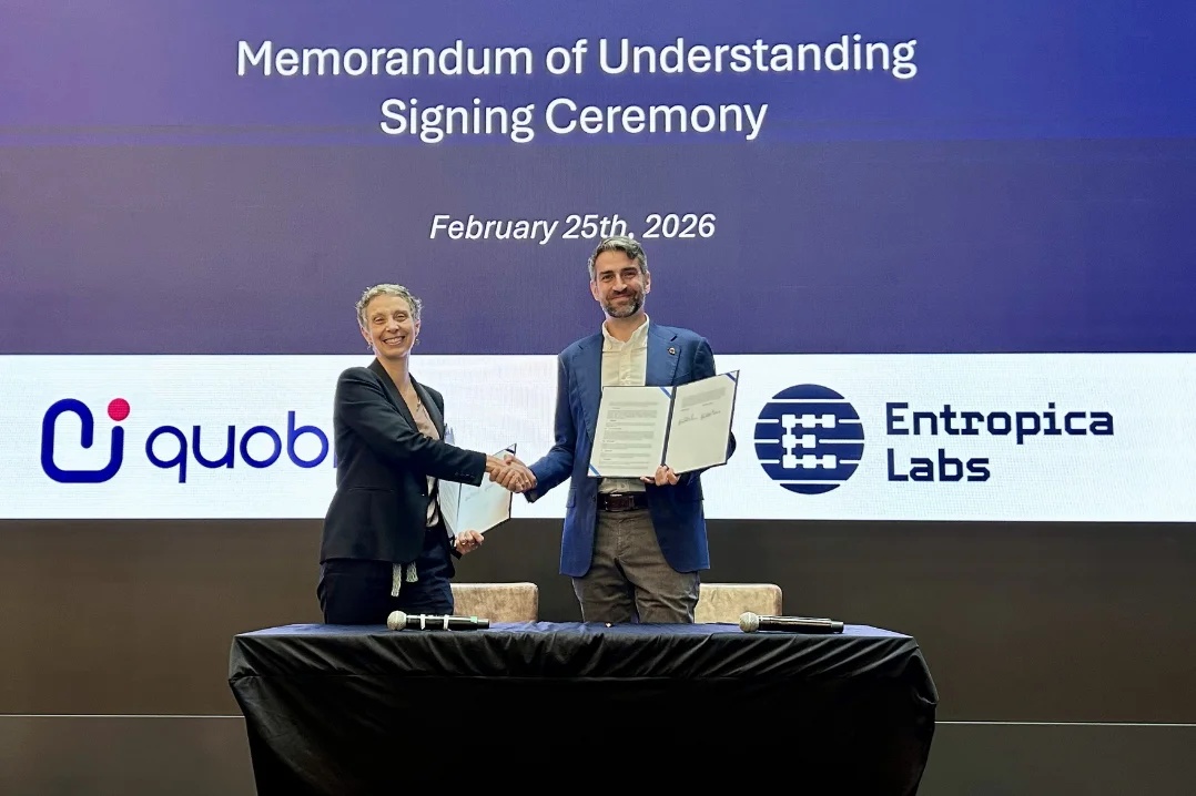 Quobly CEO Maud Vinet and Entropica Labs CEO Tommaso Demarie shaking hands and holding their signed agreement in Singapore