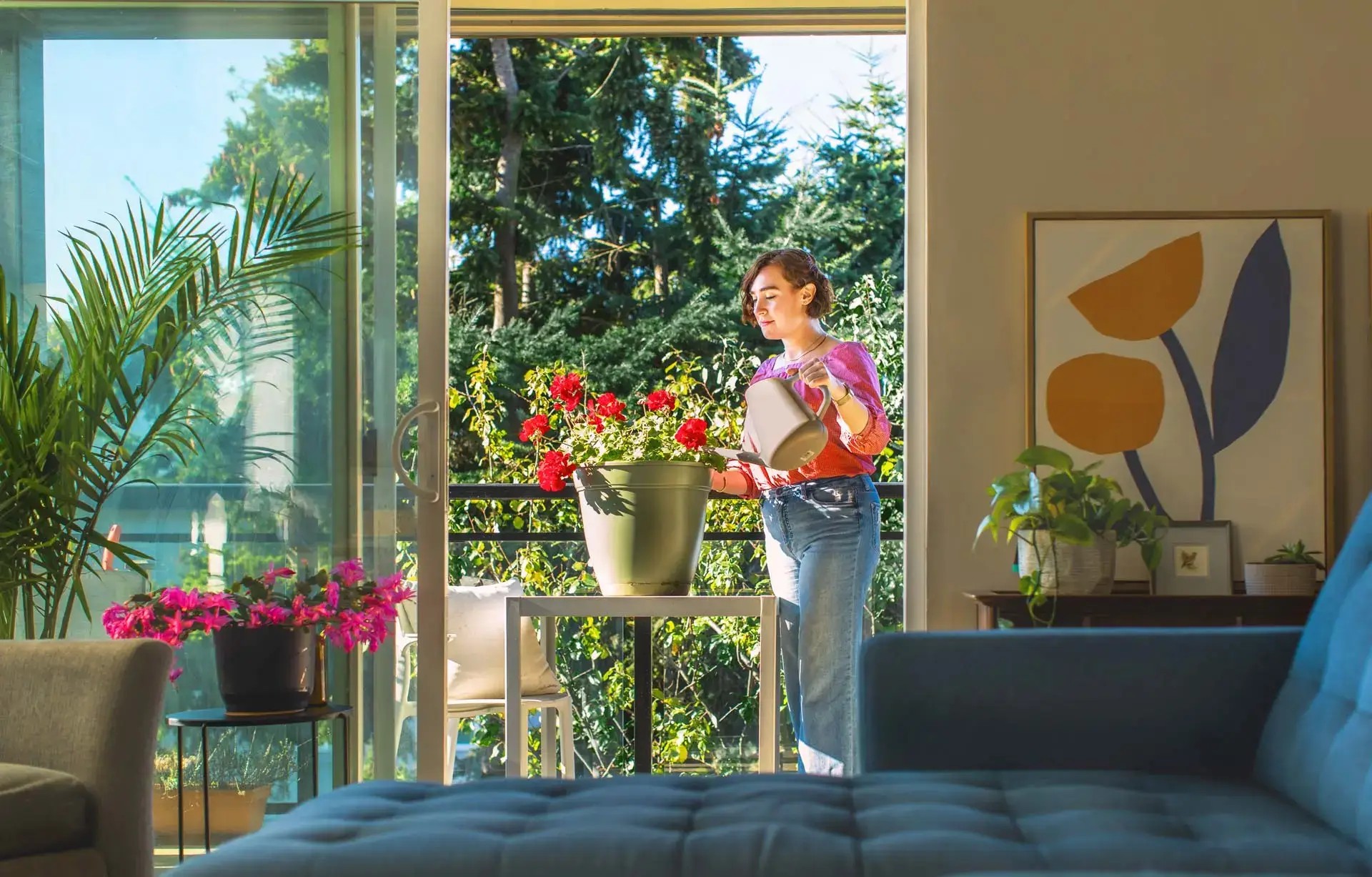 A woman watering flowers on the balcony of a bright home