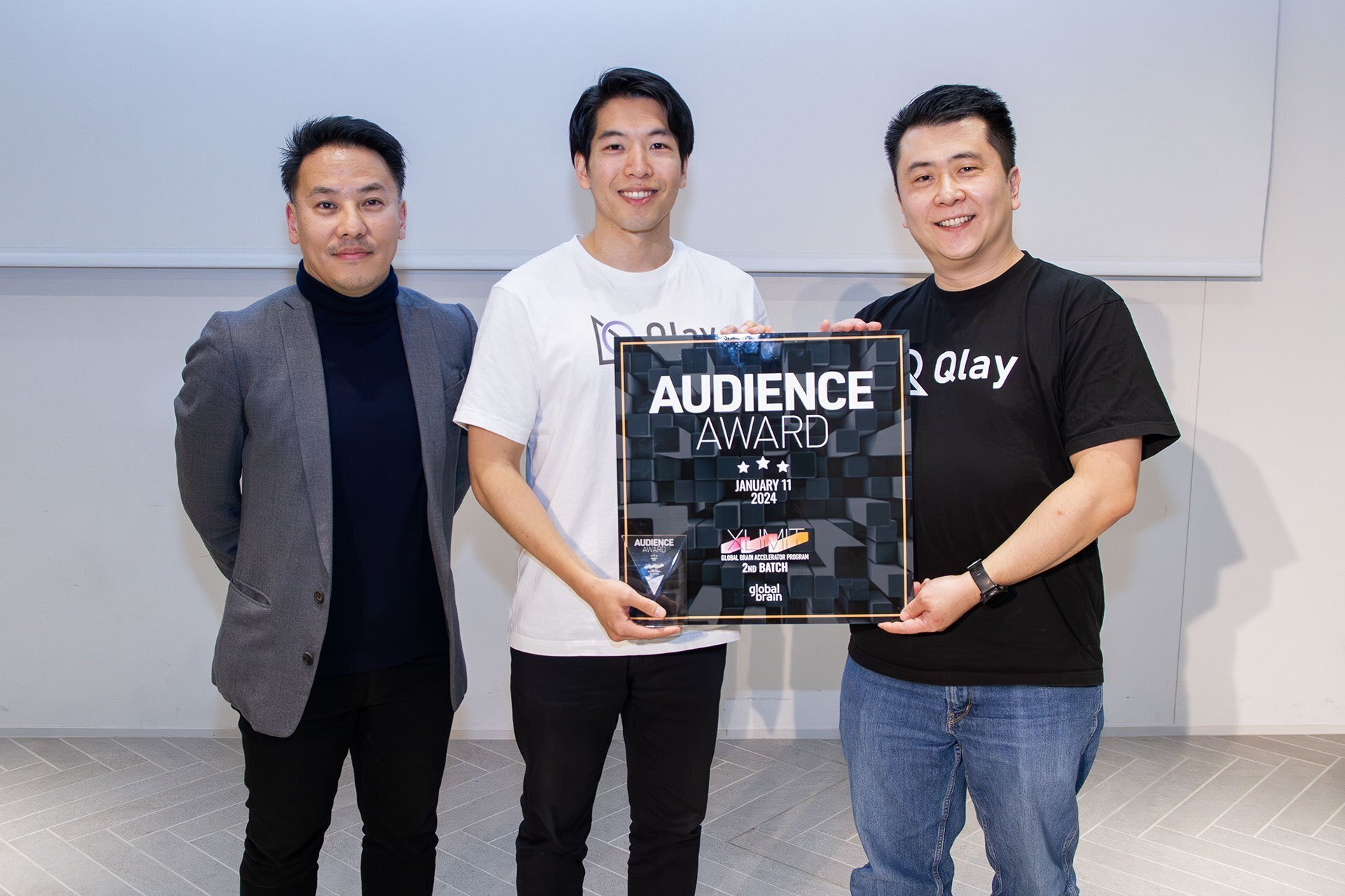 Tomofumi Nakata, center, and Tokumasa Yamashita, right, holding Qlay's XLIMIT audience award beside their mentor