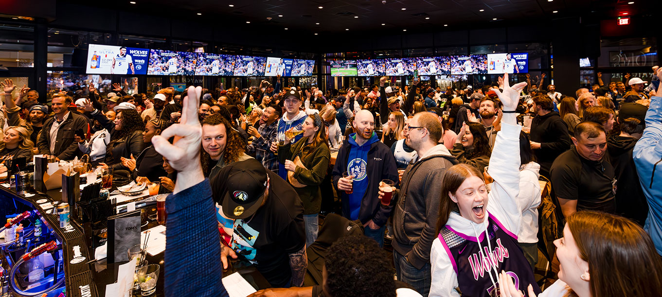 Fans cheering together inside a crowded Tom's Watch Bar