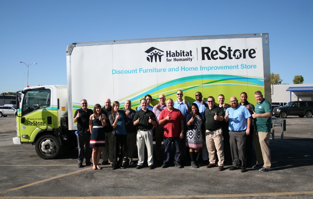 A company archive group photograph beside a Habitat for Humanity ReStore truck