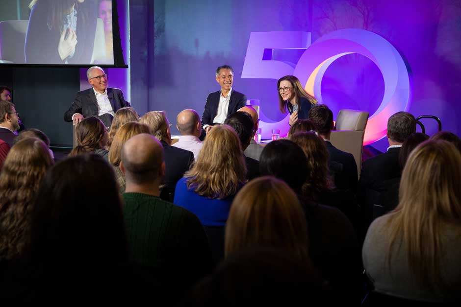 Tony Cheng, seated at center, joins an RGA town-hall panel before an audience of employees.
