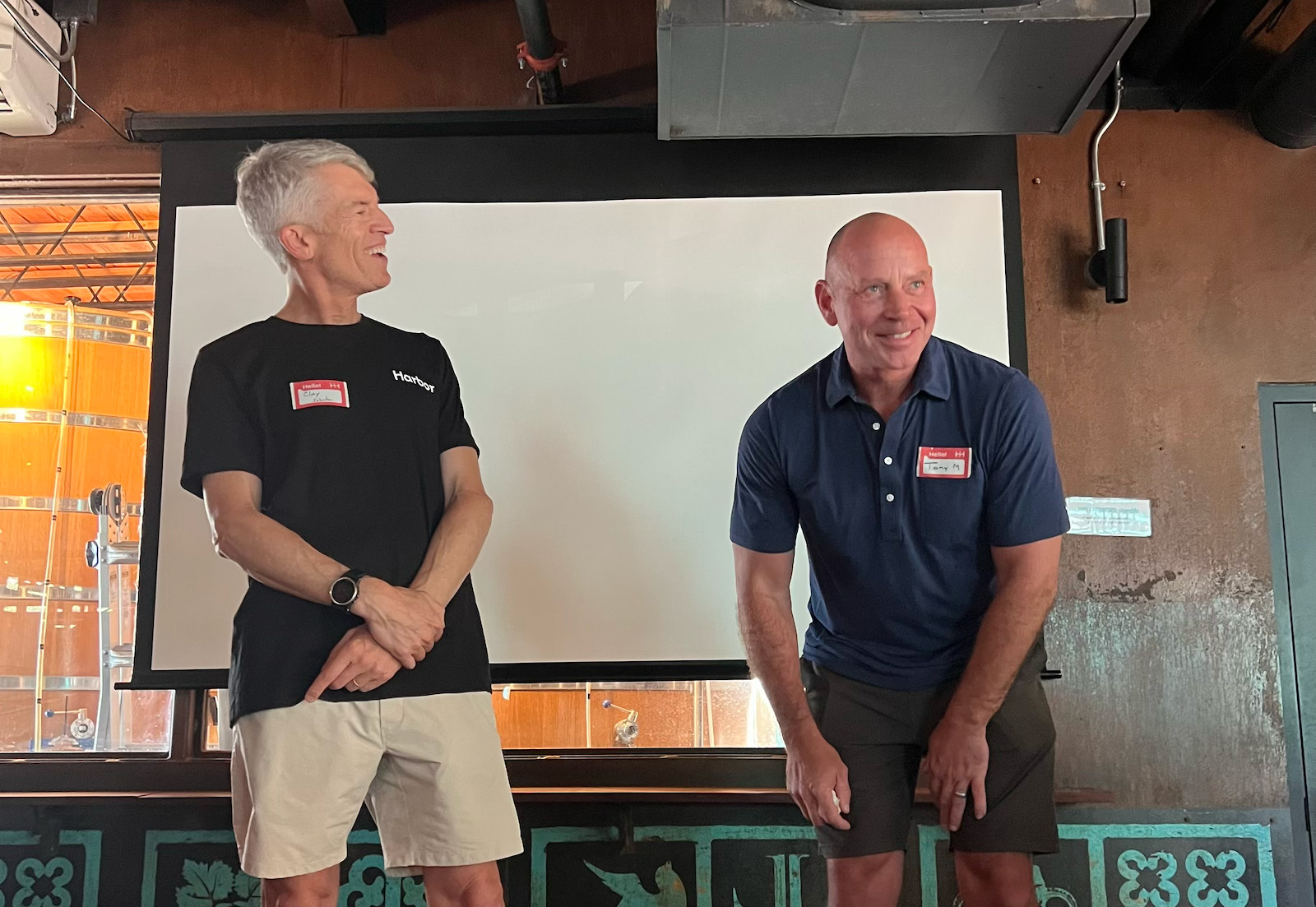 Clay Johnston and Tony Miller smiling together onstage, both wearing name tags