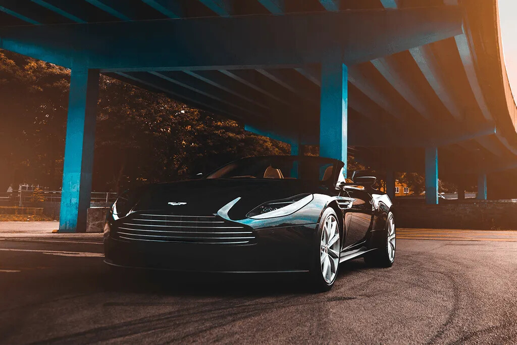 A black Aston Martin photographed beneath a concrete overpass