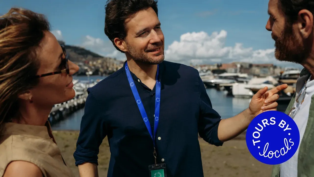 A local guide speaking with two travelers beside a harbor