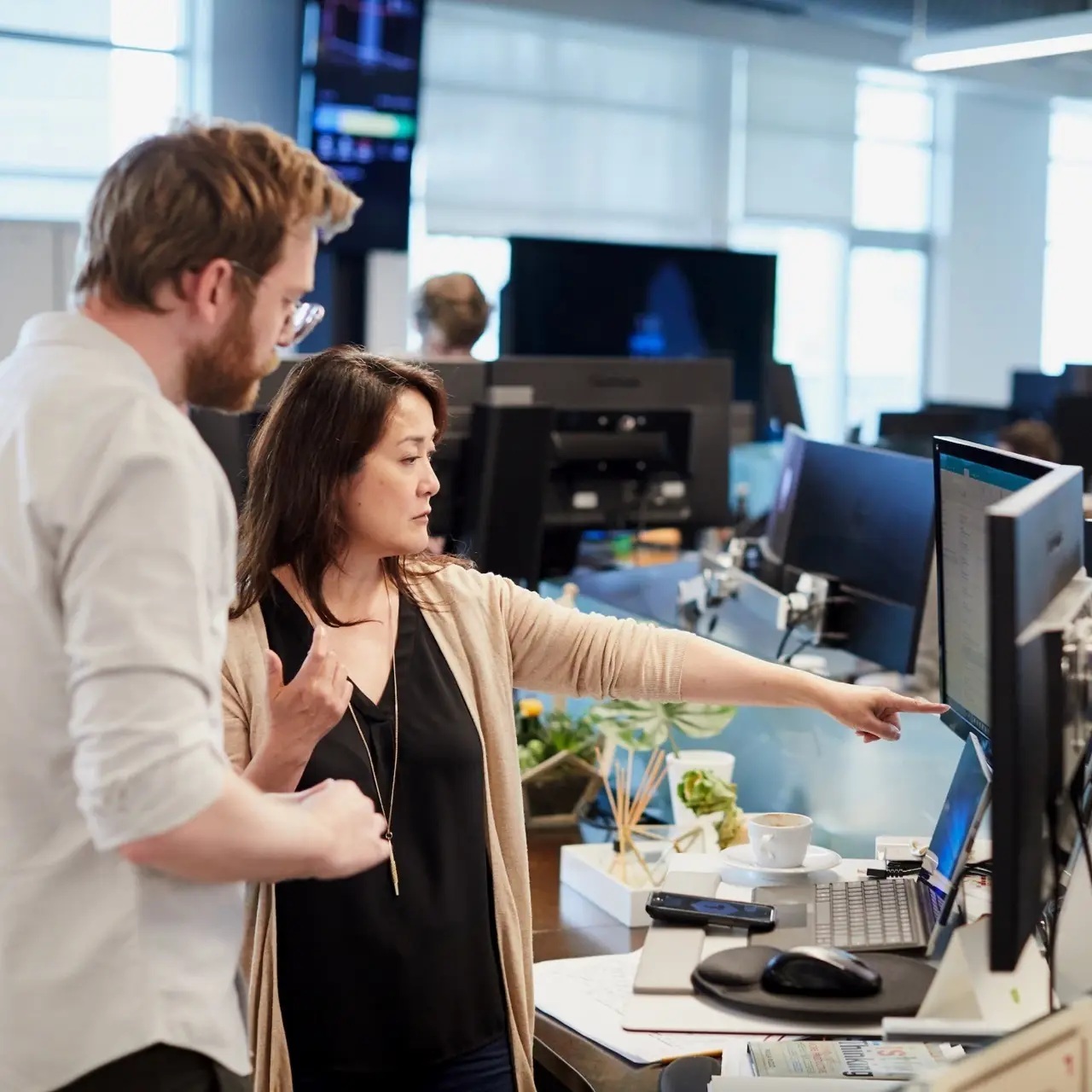 Two Toyota Connected colleagues review work at a desk with multiple monitors