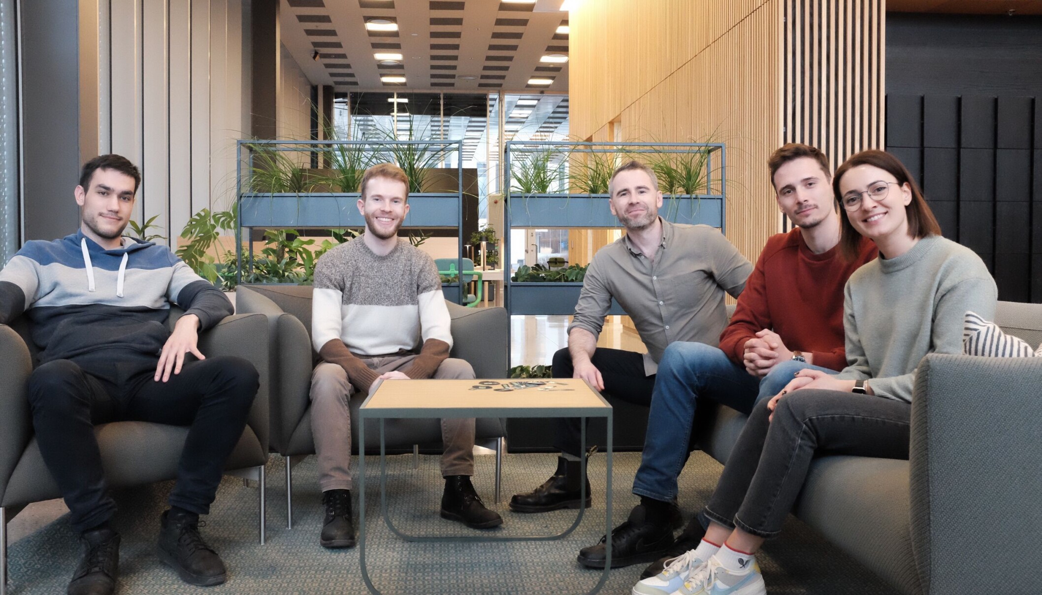 Five members of the early TP Accurate team seated in a modern office